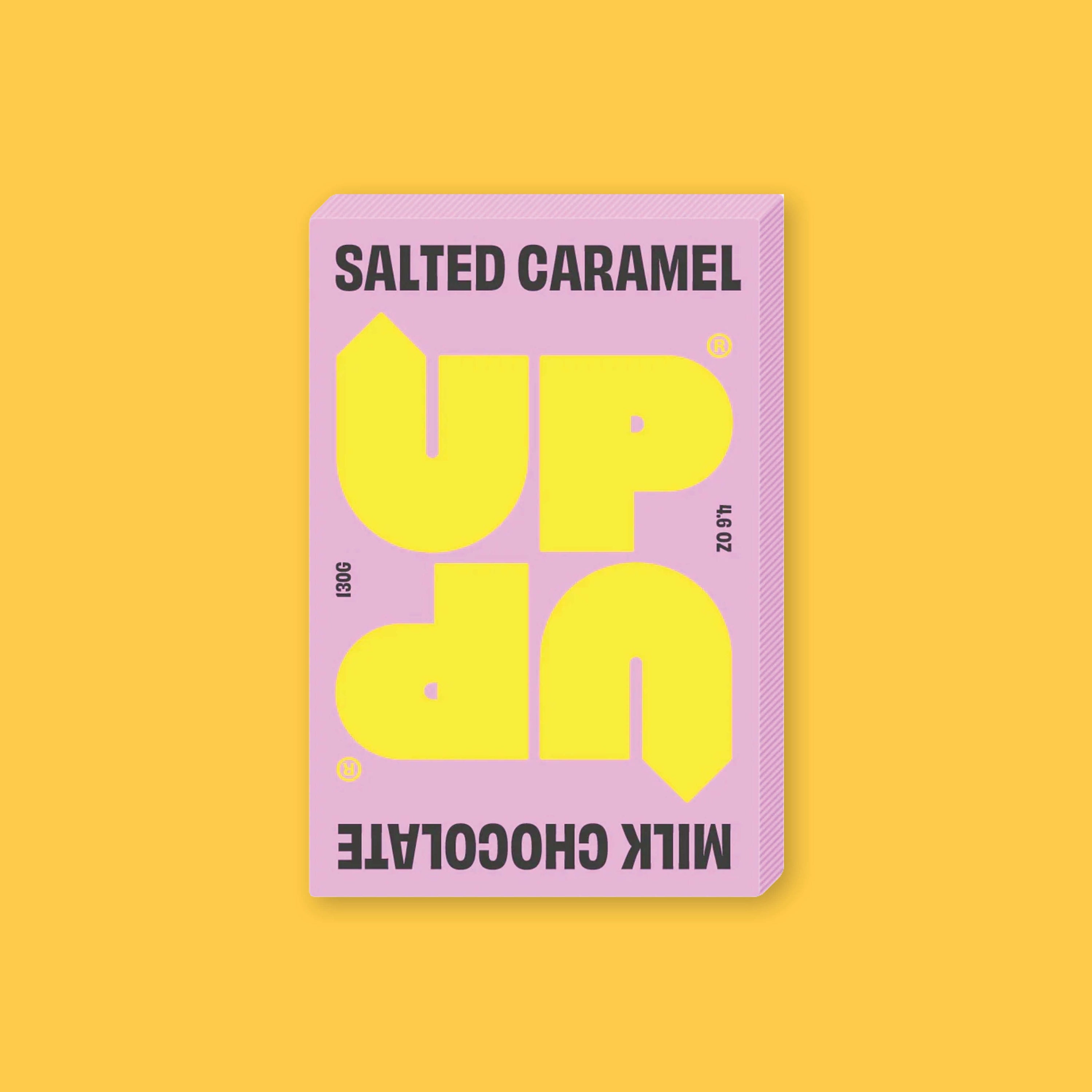 On a sunny mustard background sits a box of UP UP Salted Caramel Chocolate. The packaging is in light pink and yellow. 130G 4.6 OZ