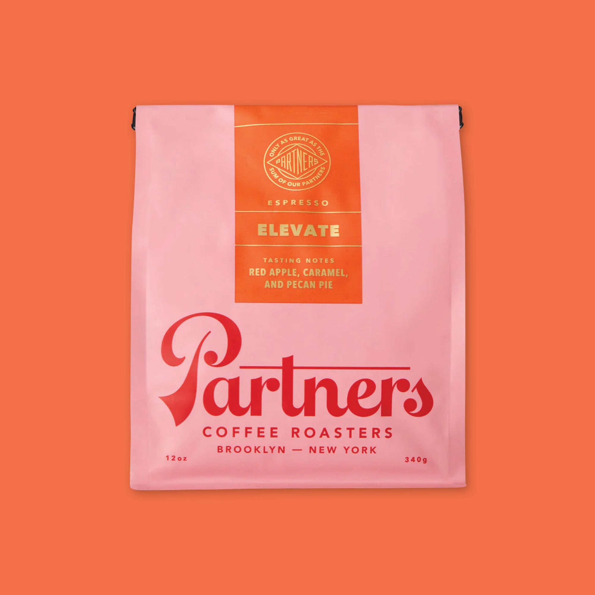 On an orangey-red background is a photo of a pink and red bag of Partners Coffee Roasters Brooklyn - New York Jumpstart Blend. Tasting notes: Red apple, caramel and pecan pie, 12 oz, 340 g