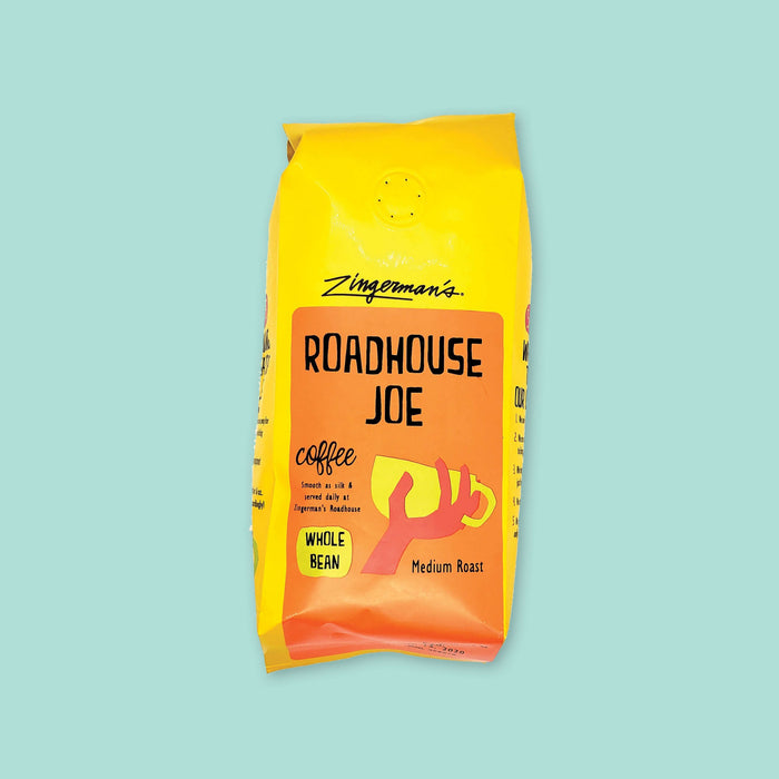 On a cool aqua background is a yellow bag of coffee. The coffee is Zingerman's brand Roadhouse Joe Blend. 'Smooth as silk and served daily at Zingerman's Roadhouse' Ground coffee. 12 oz (350 g)
