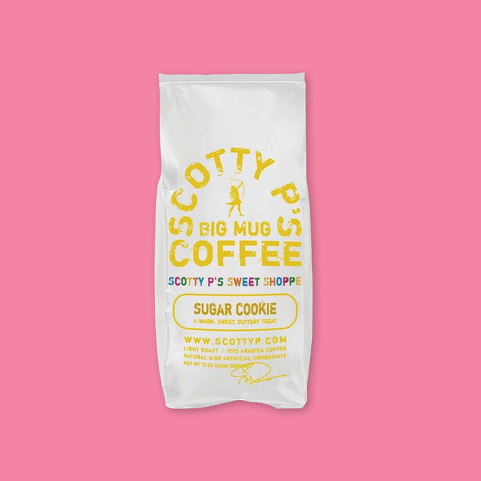 On a bubblegum pink background is a white bag of coffee. The coffee is Scotty P's Coffe Sugar Cookie Blend. It is a "warm, sweet, buttery treat." 12 oz (350g).