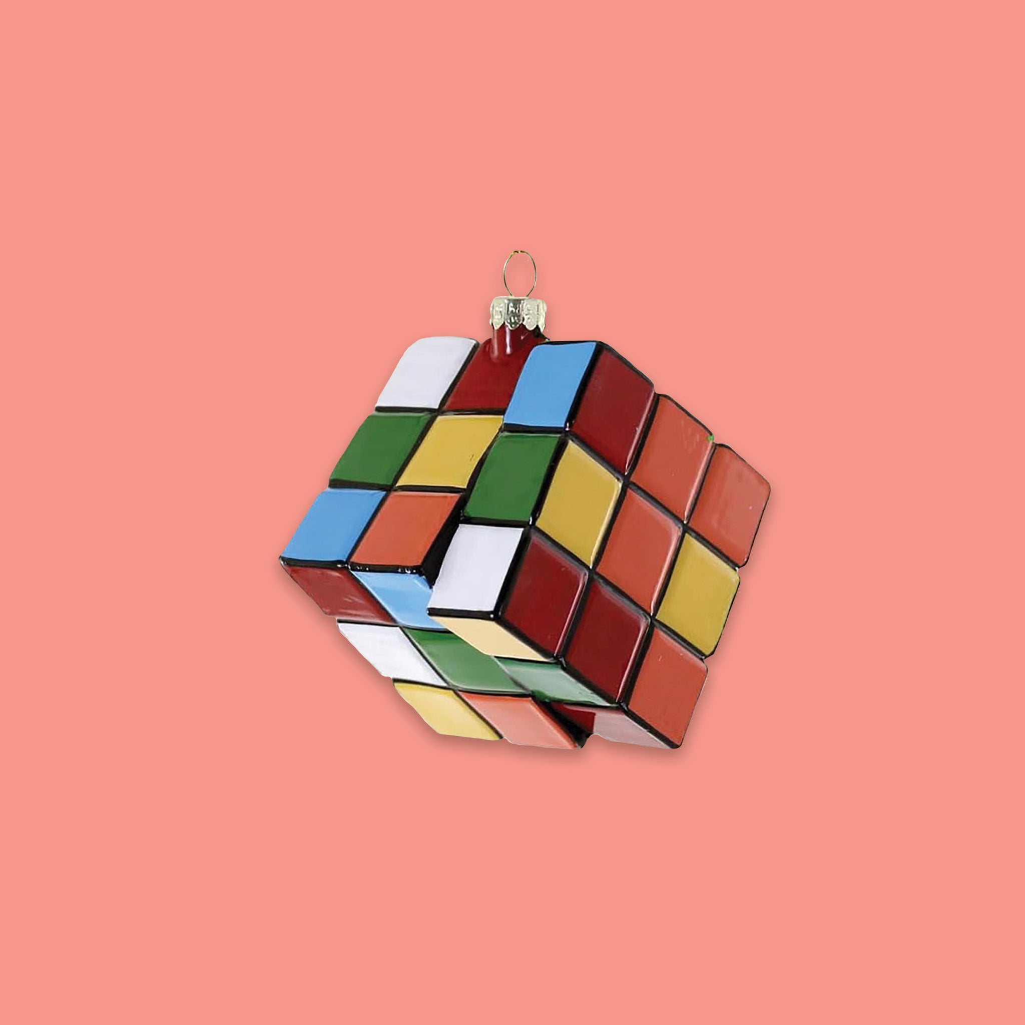 On a coral pink background sits a rubik's cube glass ornament.