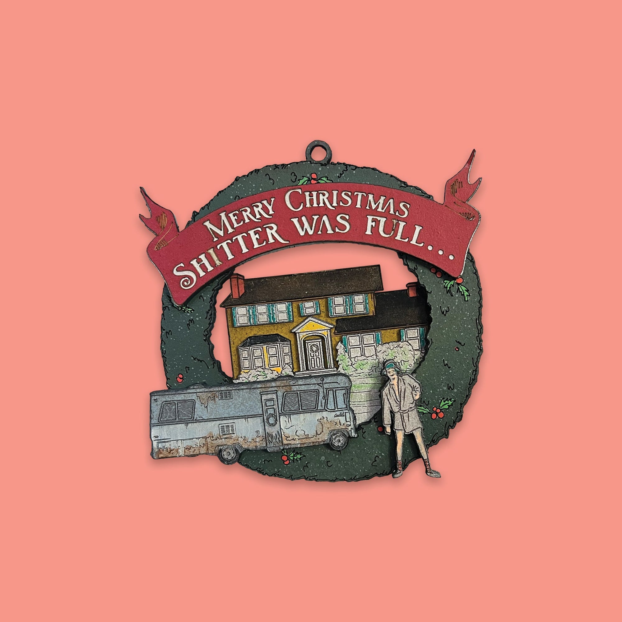 On a coral pink background sits a Christmas Vacation inspired ornament. It is of Cousin Eddie with his motorhome in front of the Griswold house. There is a red banner at the top and it says in white "MERRY CHRISTMAS SHITTER WAS FULL..."