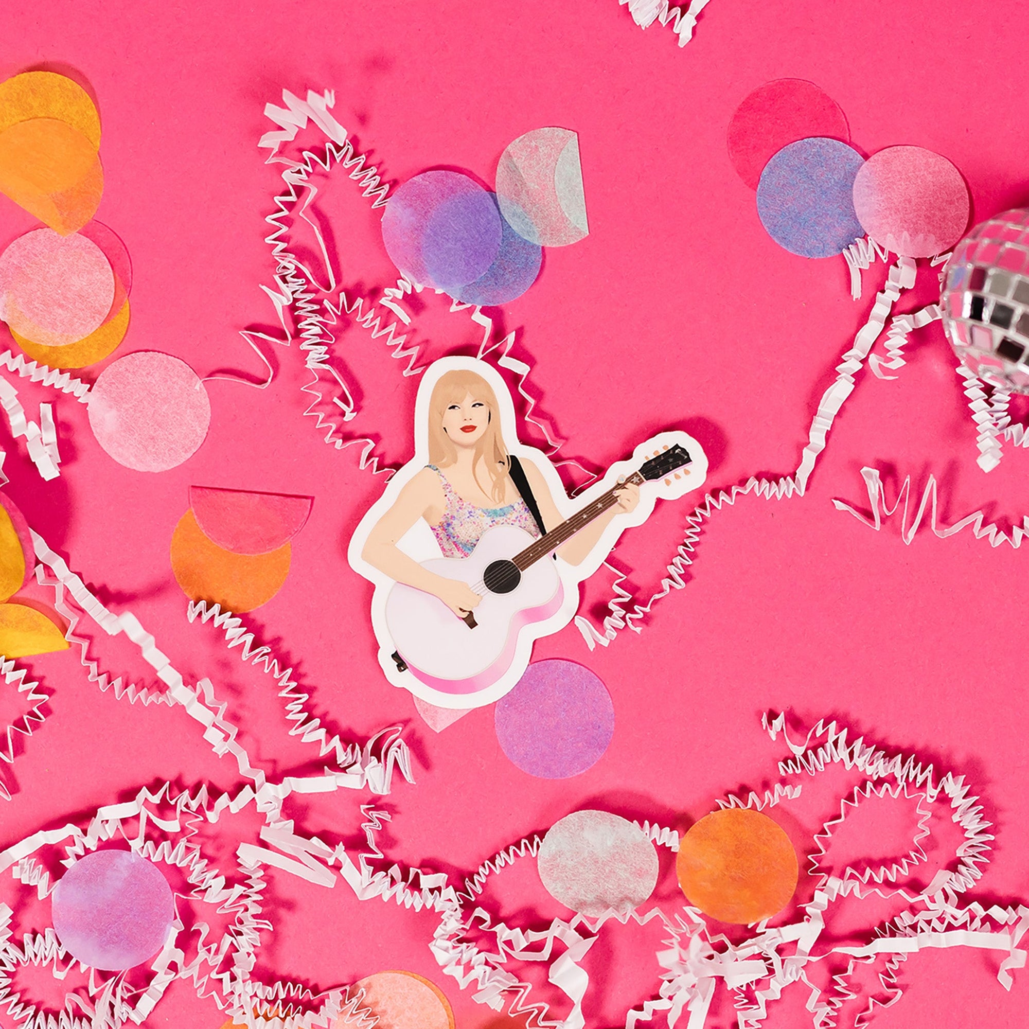 On a hot pink background sits a sticker with white crinkle and big, colorful confetti scattered around. This Taylor Swift inspired sticker is an illustration of Taylor Swift holding a pink guitar.