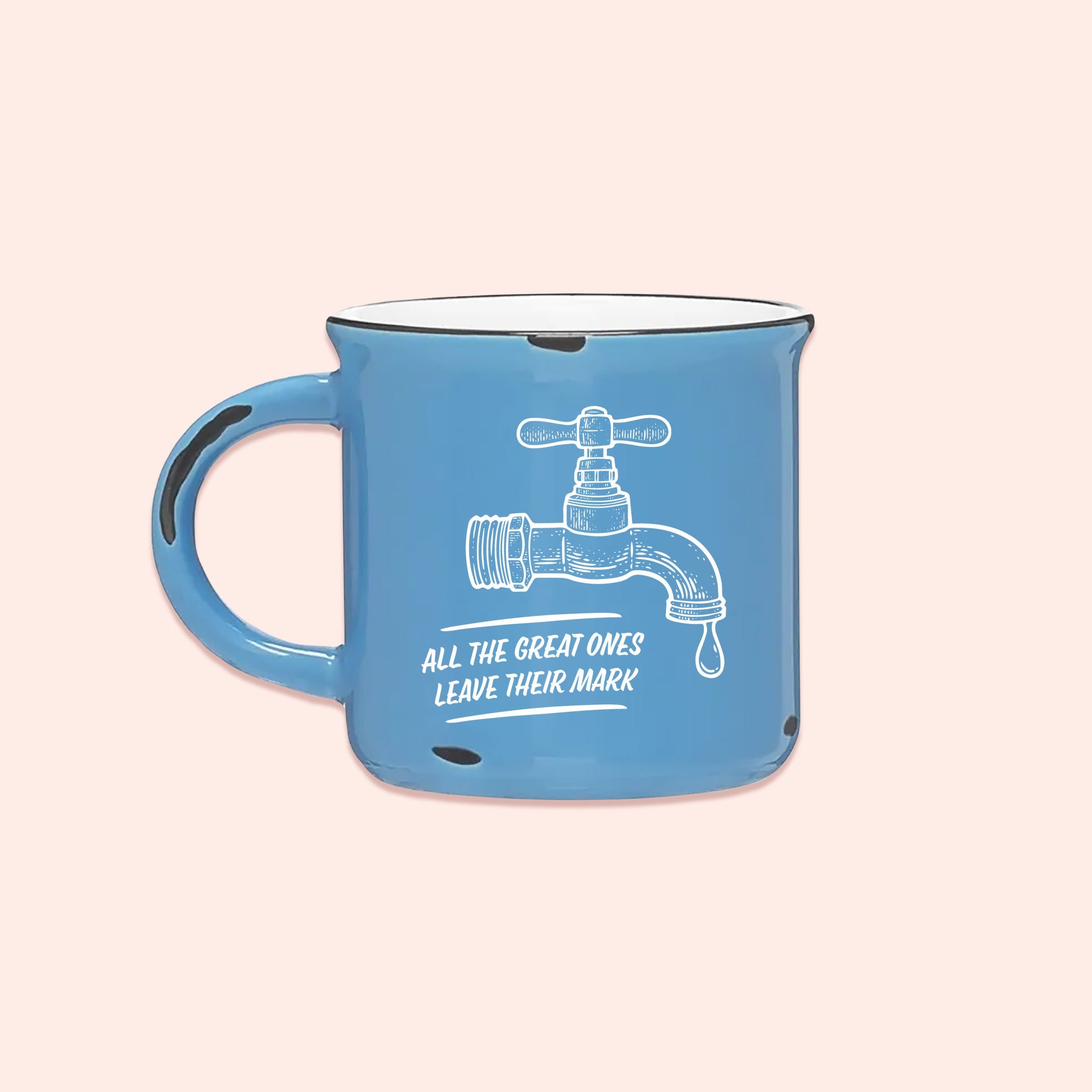 On a light pink background sits a campfire mug. This Home Alone inspired mug is light blue with white lettering and an illustration of a water faucet in white. It says "ALL THE GREAT ONES LEAVE THEIR MARK."