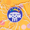 On a sunny mustard background sits a sticker with white crinkle and big, colorful confetti scattered around. This brilliant blue purple round sticker has a white illustration of an open book a rainbow and 5 yellow stars above it. It says "BOOK IT!" in a white, bubble text. 