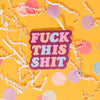On a sunny mustard background sits a sticker with white crinke and big, colorful confetti scattered around. This raspberry colored sticker says "FUCK THIS SHIT" in a fat, serif font in pink, peach and baby blue.