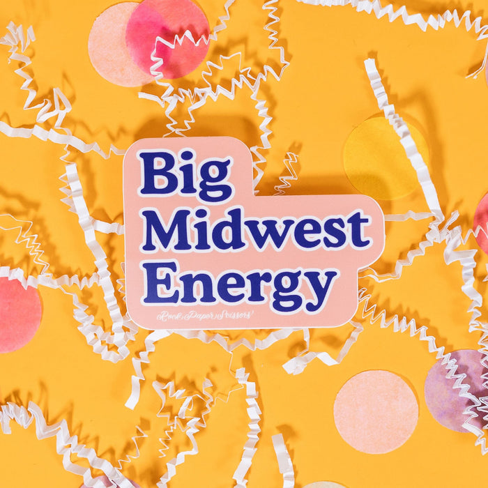 On a sunny mustard background sits a sticker with white crinkle and big, colorful confetti scattered around. This blush sticker says "Big Midwest Energy" in brilliant blue serif font with a white outline. Under it says "Rock Paper Scissors" in white handwritten script lettering. 2"-3"