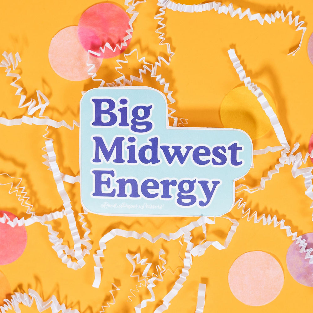 On a sunny mustard background sits a sticker with white crinkle and big, colorful confetti scattered around. This light blue sticker says "Big Midwest Energy" in brilliant blue serif font with a white outline. Under it says "Rock Paper Scissors" in white handwritten script lettering. 2"-3"