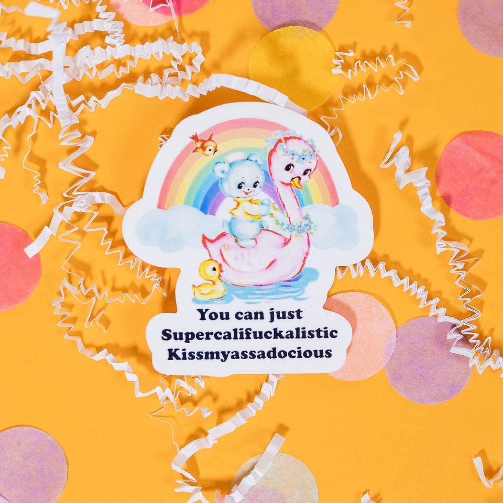 On a sunny mustard background sits a sticker with white crinkle and big, colorful confetti scattered around. This white sticker has a vintage pastel illustration of a swan in water with a furry bear on it. There is a baby duckling, a bird with a rainbow with clouds. It says "You can just Supercalifuckalistic Kissmyassadocious" in thick, black serif font. 3"
