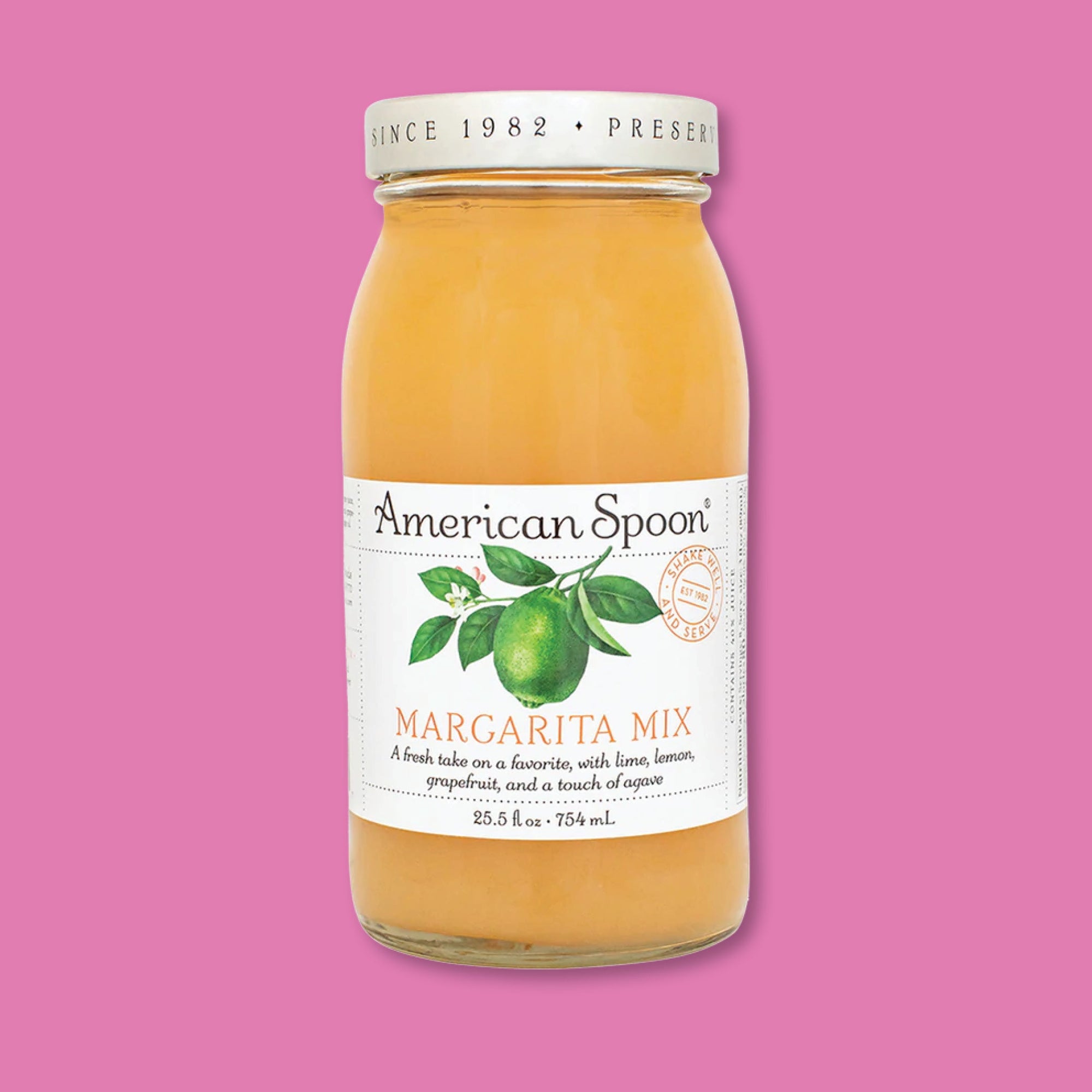 On a raspberry pink background sits a bottle. This glass bottle has a white lable with an illustration of a lime on a branch. It says "American Spoon MARGARITA MIX" in a serif font in black and orange. Under it says "A fresh take on a favorite, with lime, lemon, grapefruit, and a touch of agave" in a black, serif italic font. 25.5 fl oz • 754 mL